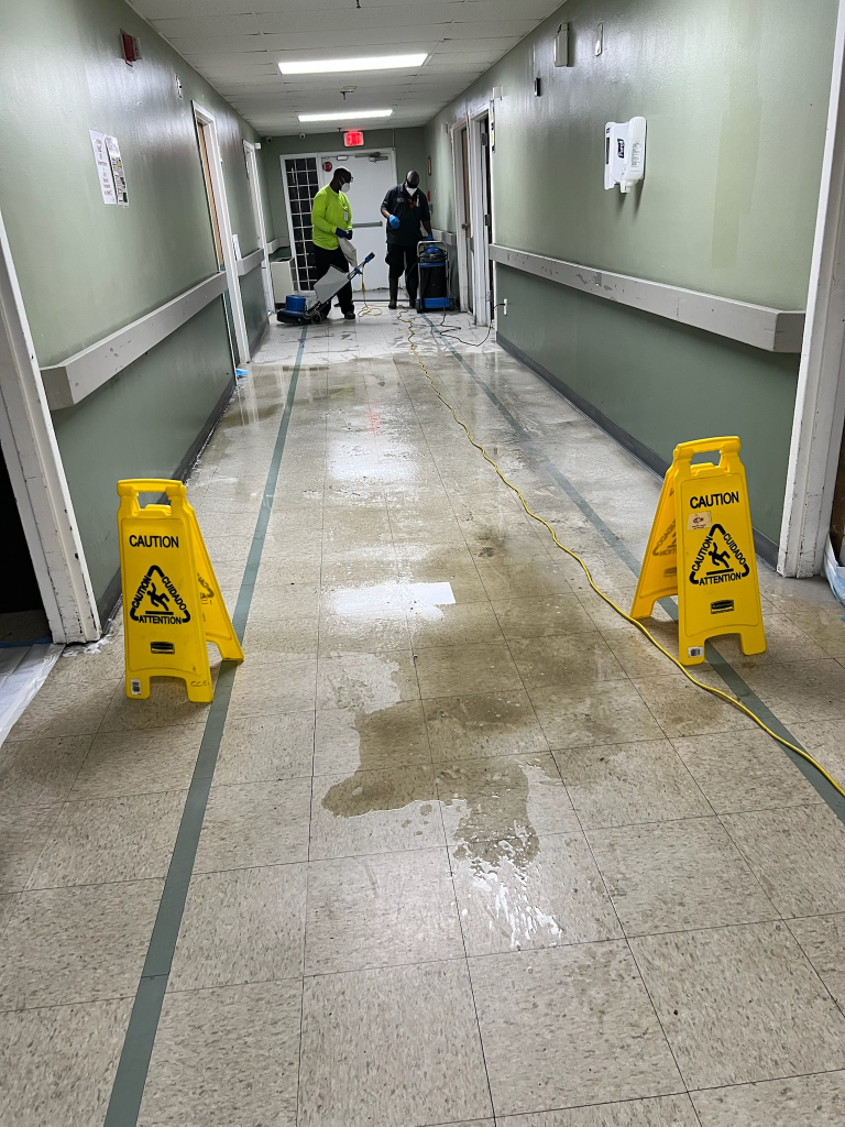 dirty hospital hallway with caution yellow signs placed due to cleaning