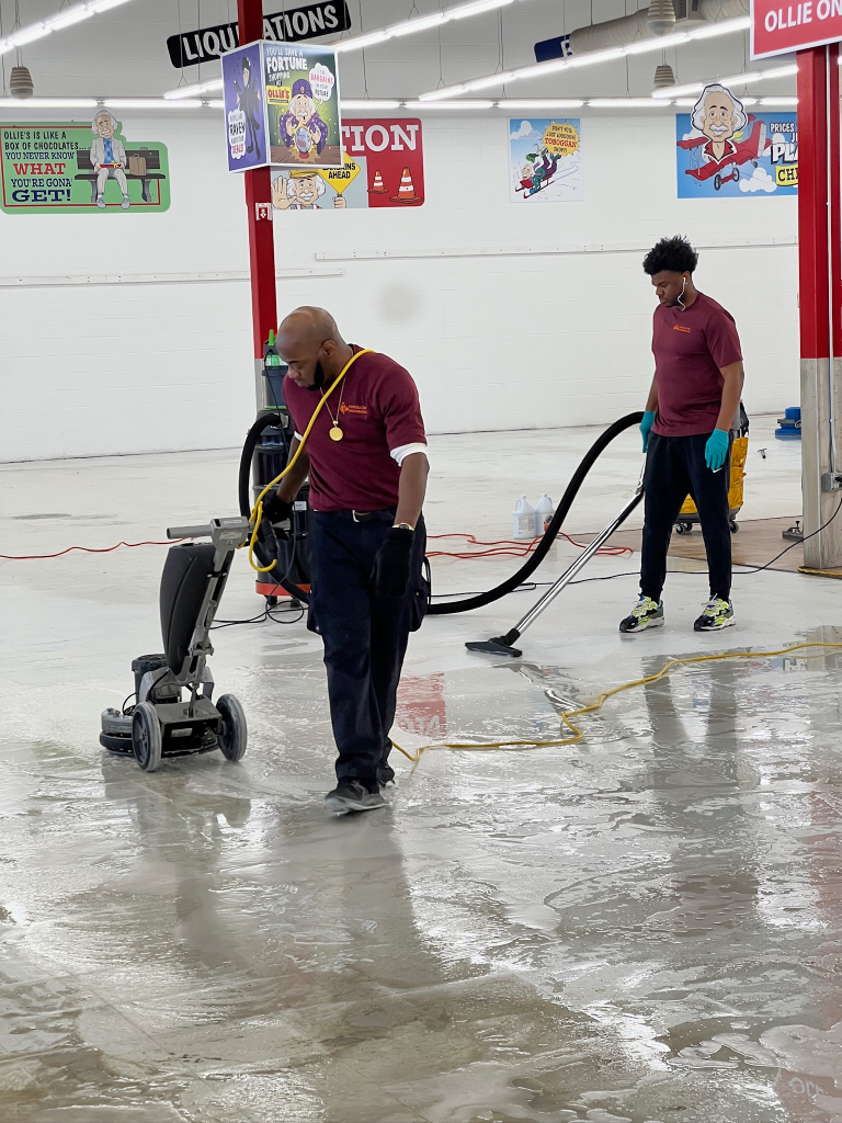 janitors wearing red uniforms using high-pressure vacuums and scrubbers to clean the floor