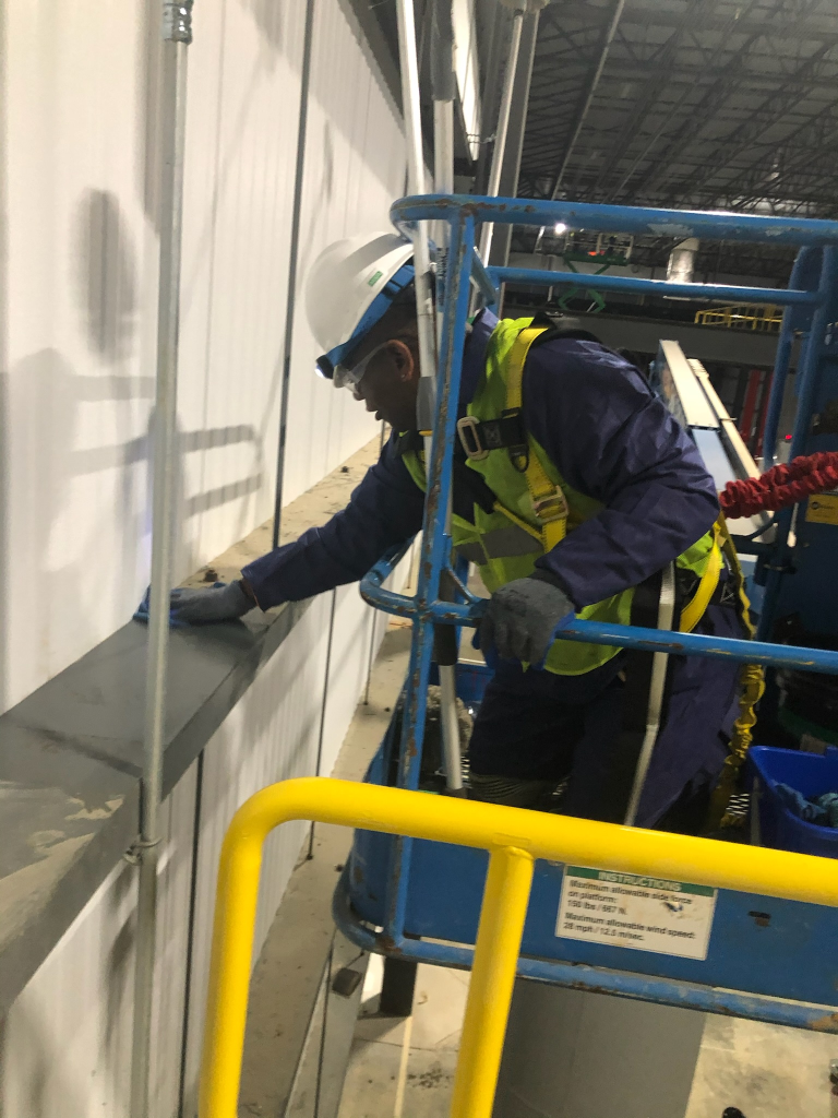 a person on a crane cleaning the high points of a warehouse