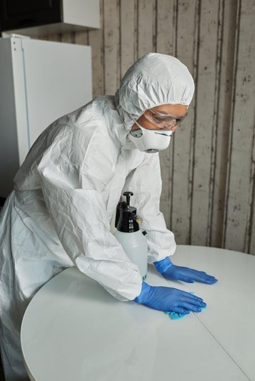 An image of a person wearing PPE cleaning a table at a hospital