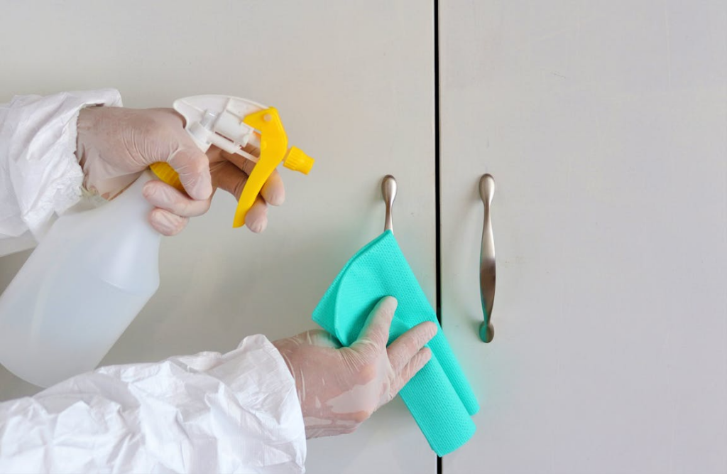 A person wearing latex gloves to disinfect hospital cabinets.